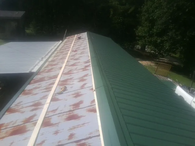 Old rusted panels beside newly installed green metal roofing — Wind Damage Roof Repair by Roofing Brothers in Pocomoke City