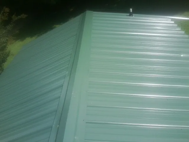 New green metal panels meeting at the ridge of a roof — Flat Roof Repair work by our crew in Pocomoke City