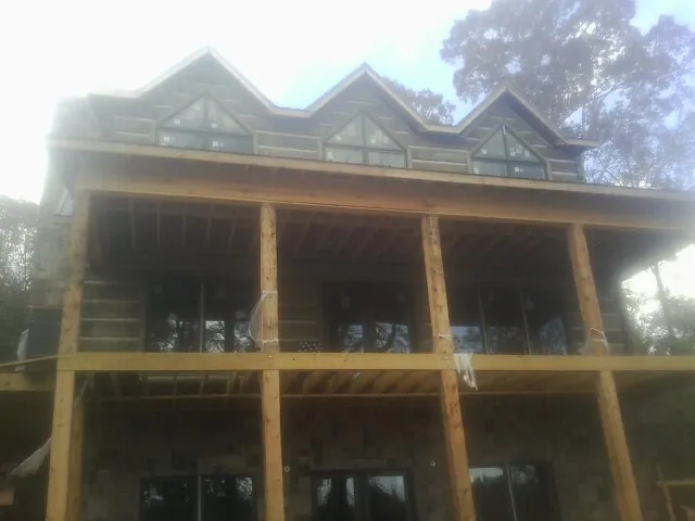 Dormers and porch framing on a large log home under construction — Roof Coating work by our crew in Pocomoke City