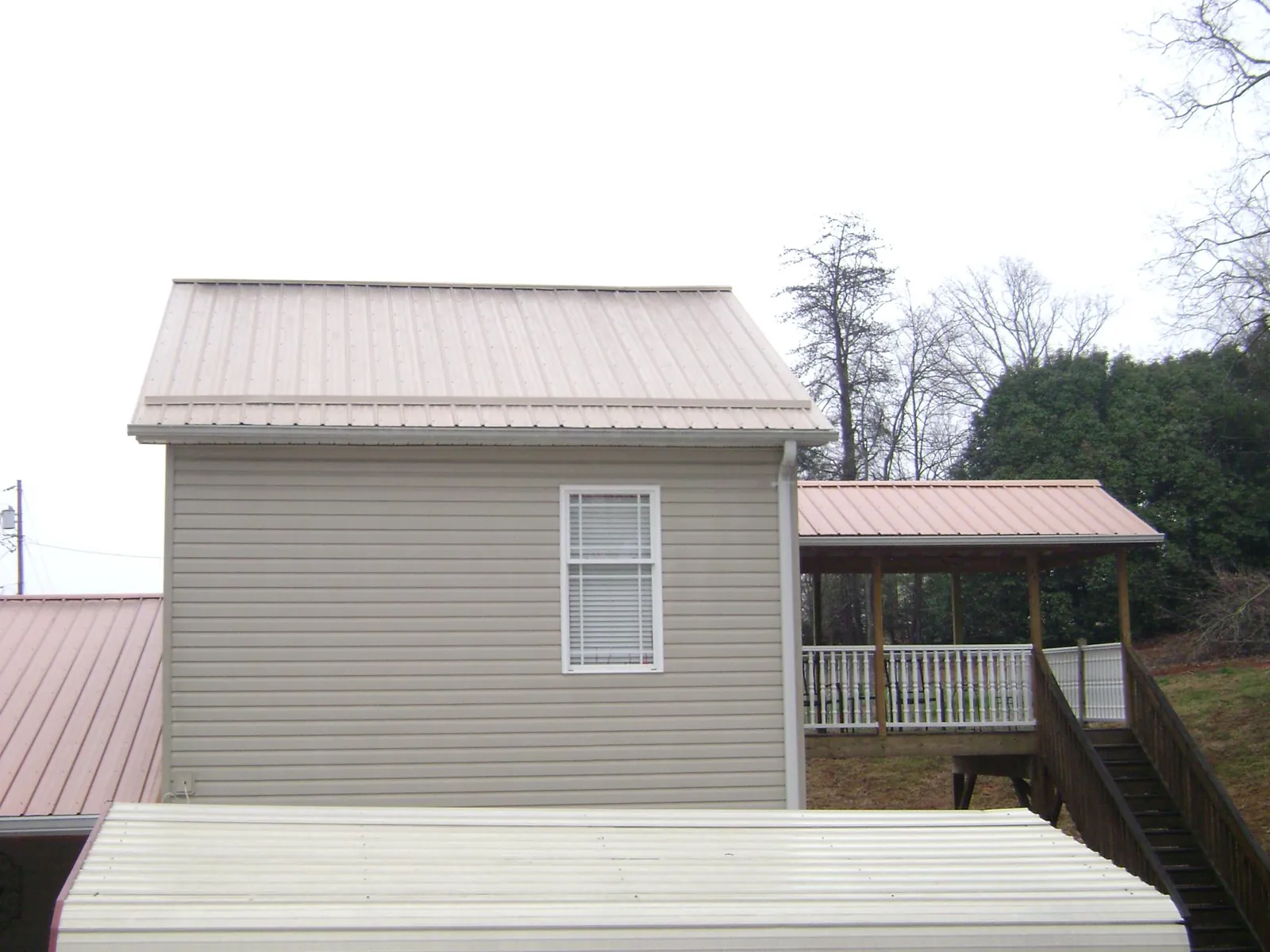 Tan metal roofs on a two story addition and attached porch, from a Roof Replacement job in Pocomoke City