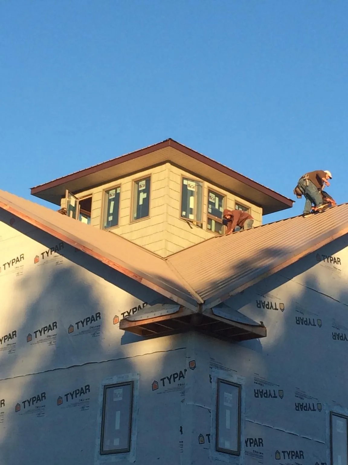 Roofers working around a rooftop cupola on a new metal roof at sunset — Roof Waterproofing in Pocomoke City by Roofing Brothers